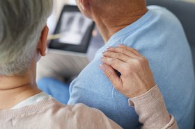 Beim Arzt: Frau legt ihre Hand auf die Schulter ihres kranken Angehörigen
