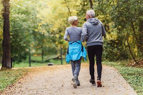 Seniorenpaar joggt auf einem Waldweg